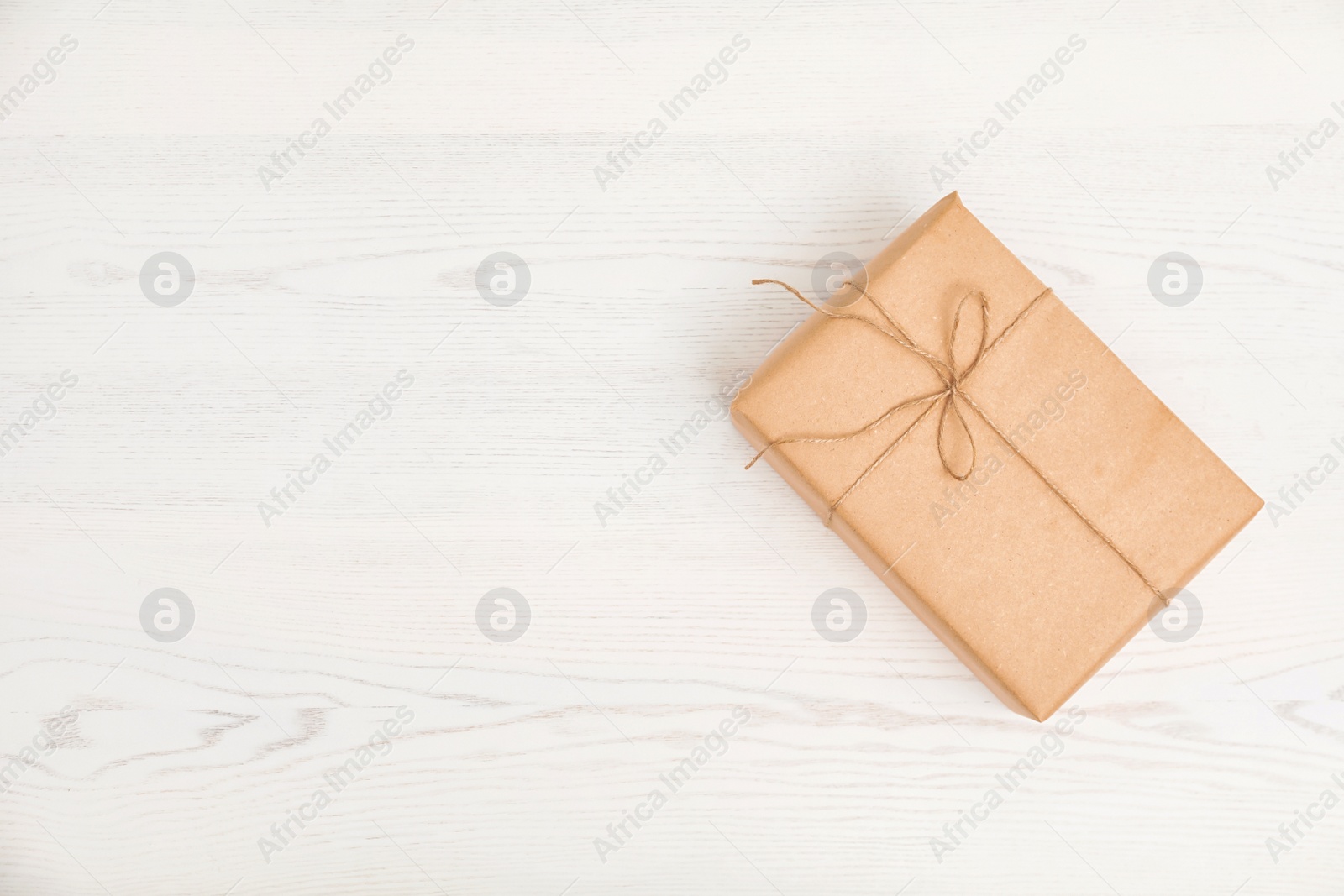 Photo of Parcel decorated with twine and space for text on wooden background, top view