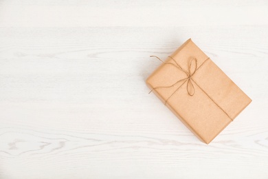 Photo of Parcel decorated with twine and space for text on wooden background, top view