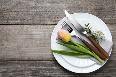 Stylish table setting with cutlery and flowers on wooden background, top view. Space for text