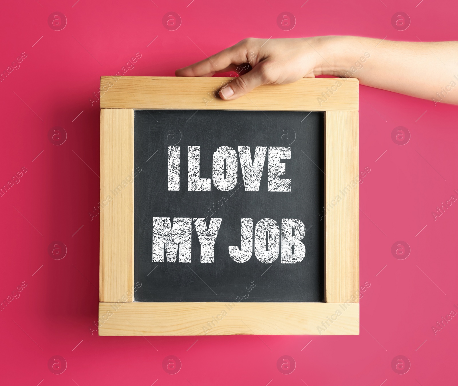 Image of Employee engagement concept. Woman holding chalkboard with text I Love My Job on pink background, closeup