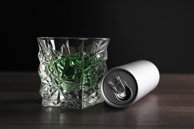 Photo of Energy drink in glass and aluminium can on wooden table, closeup