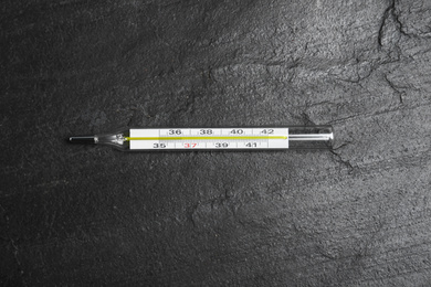 Photo of Mercury thermometer on black slate background, top view