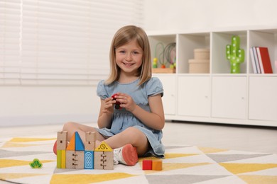 Photo of Cute little girl playing with wooden toys indoors, space for text