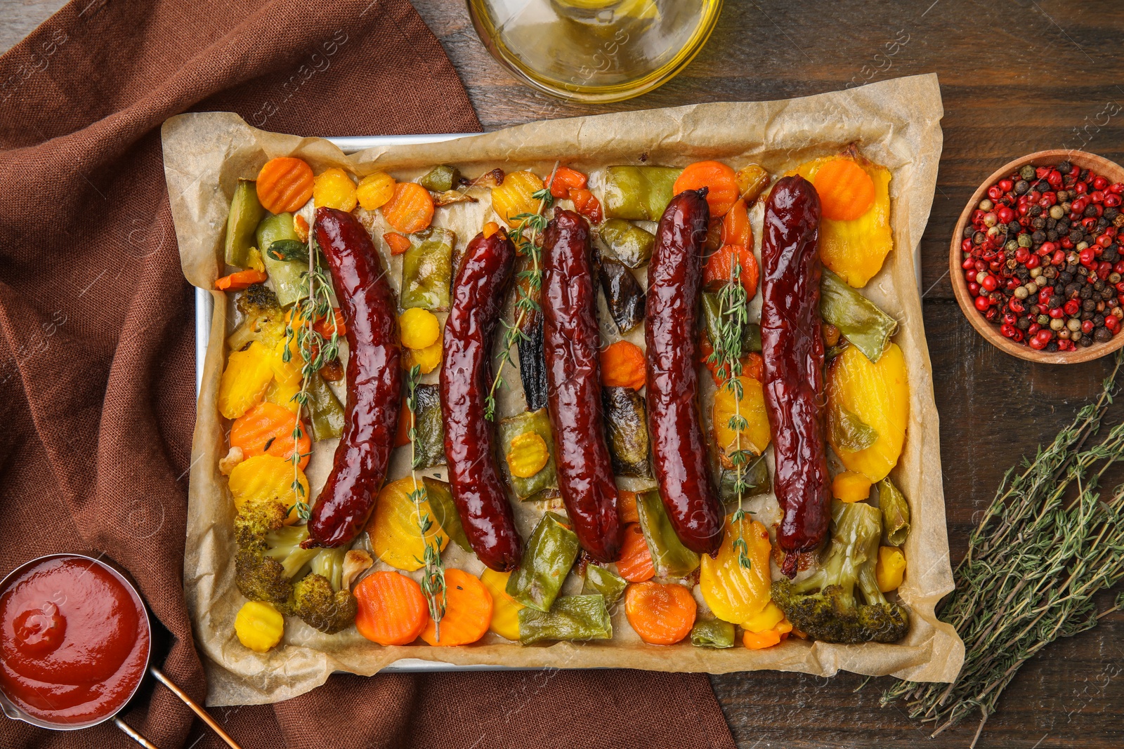 Photo of Baking tray with delicious smoked sausages and ingredients on wooden table, flat lay