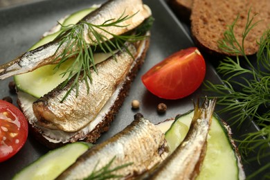 Photo of Delicious sandwiches with sprats, cucumber and dill served on plate, closeup