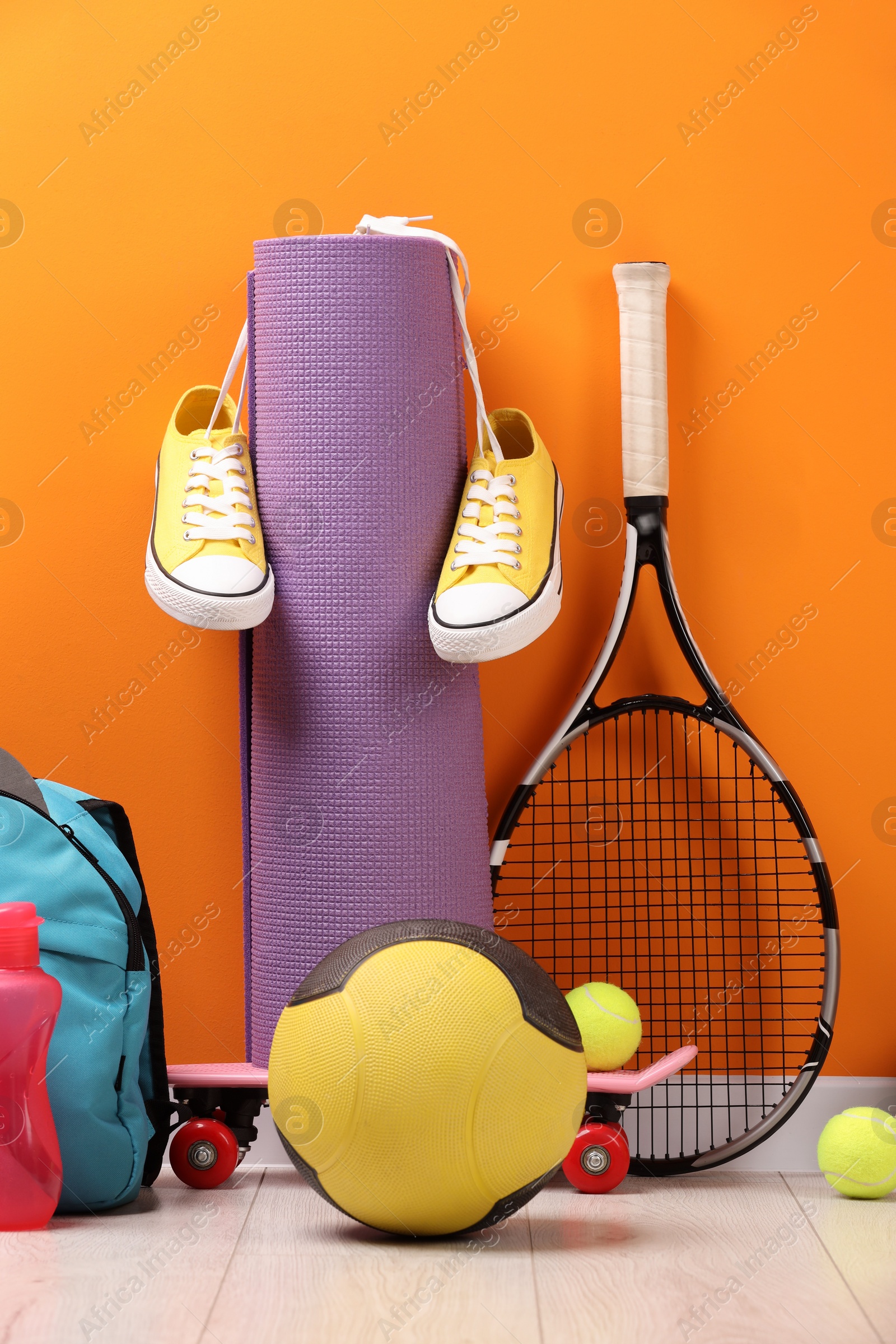 Photo of Many different sports equipment near orange wall indoors