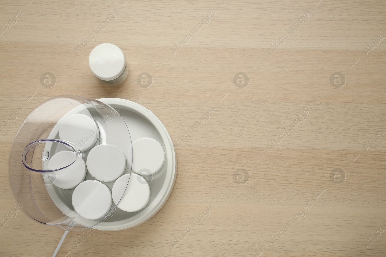 Photo of Modern yogurt maker with jars on wooden table, flat lay. Space for text