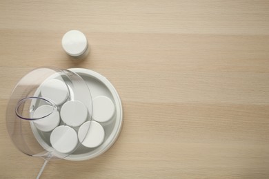 Photo of Modern yogurt maker with jars on wooden table, flat lay. Space for text