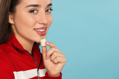 Photo of Woman with chewing gum on light blue background, closeup. Space for text