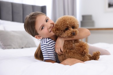 Little child hugging cute puppy on bed at home. Lovely pet