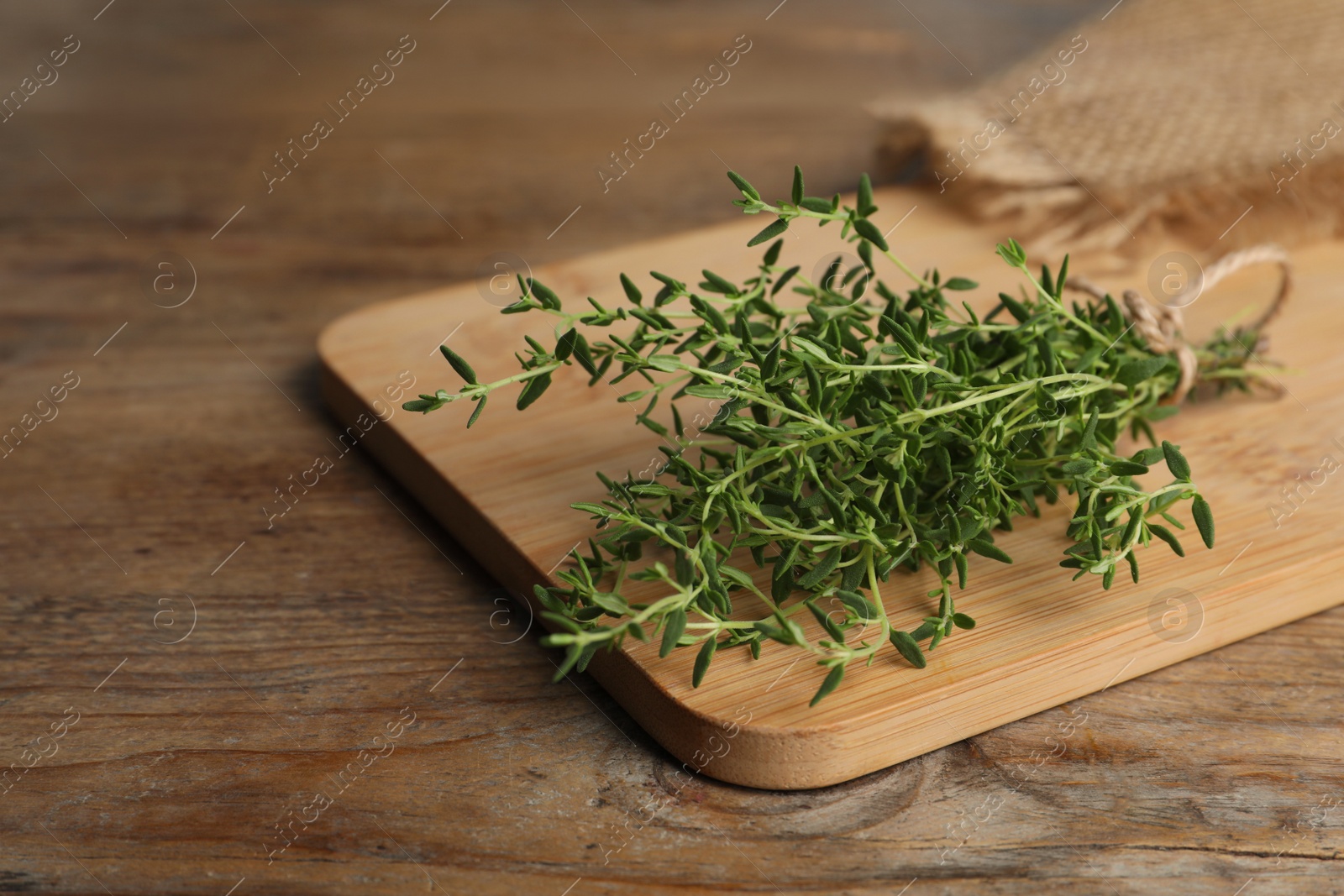 Photo of Bunch of aromatic thyme on wooden table, closeup. Space for text