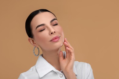 Photo of Beautiful young woman with elegant earrings on beige background