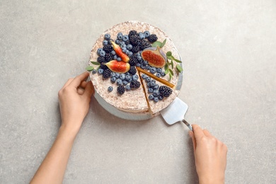 Woman and delicious homemade cake with fresh berries on table, top view