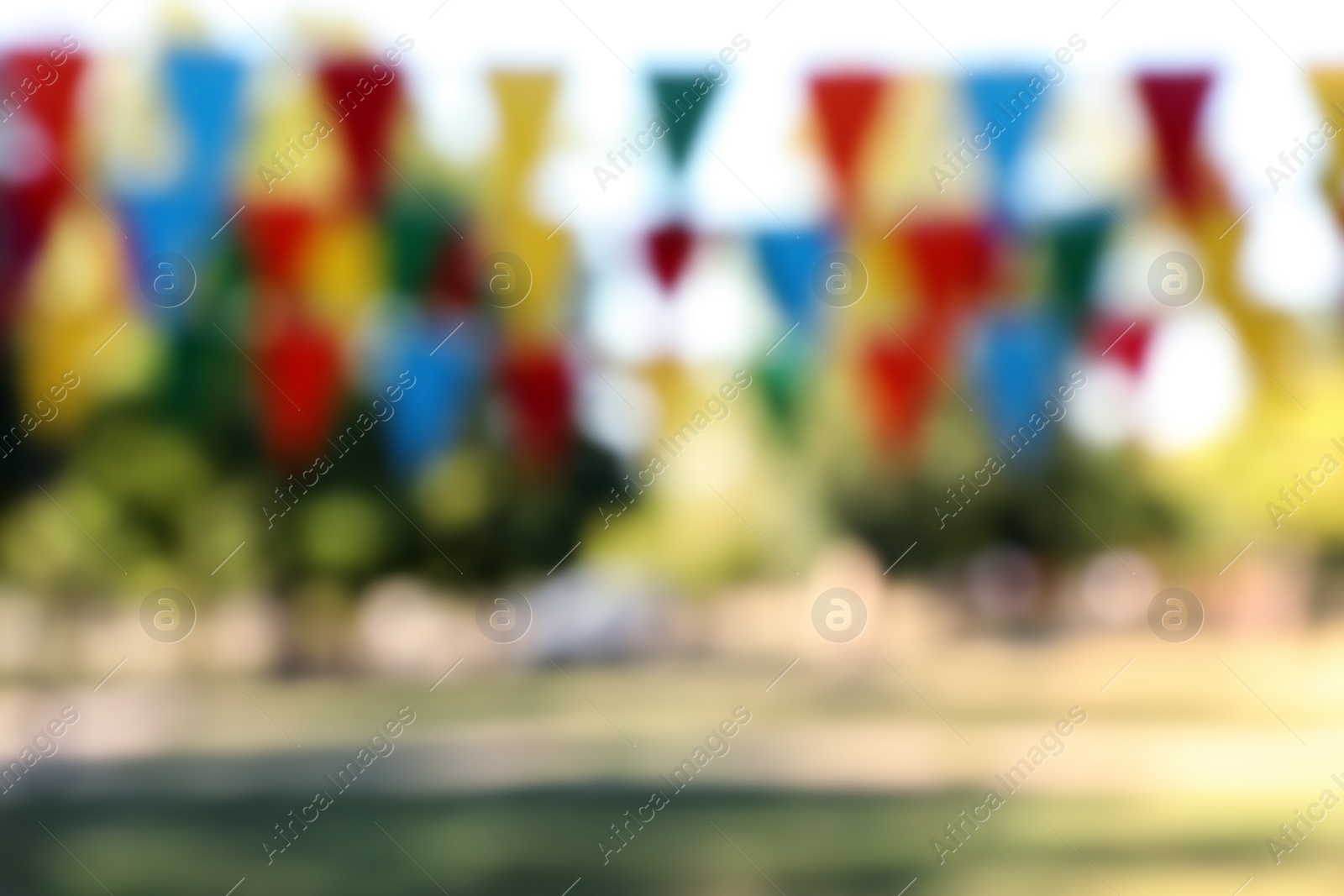 Photo of Blurred view of colorful bunting flags in park. Party decor