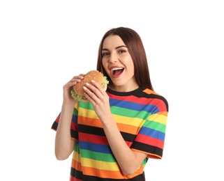 Young woman eating tasty burger on white background
