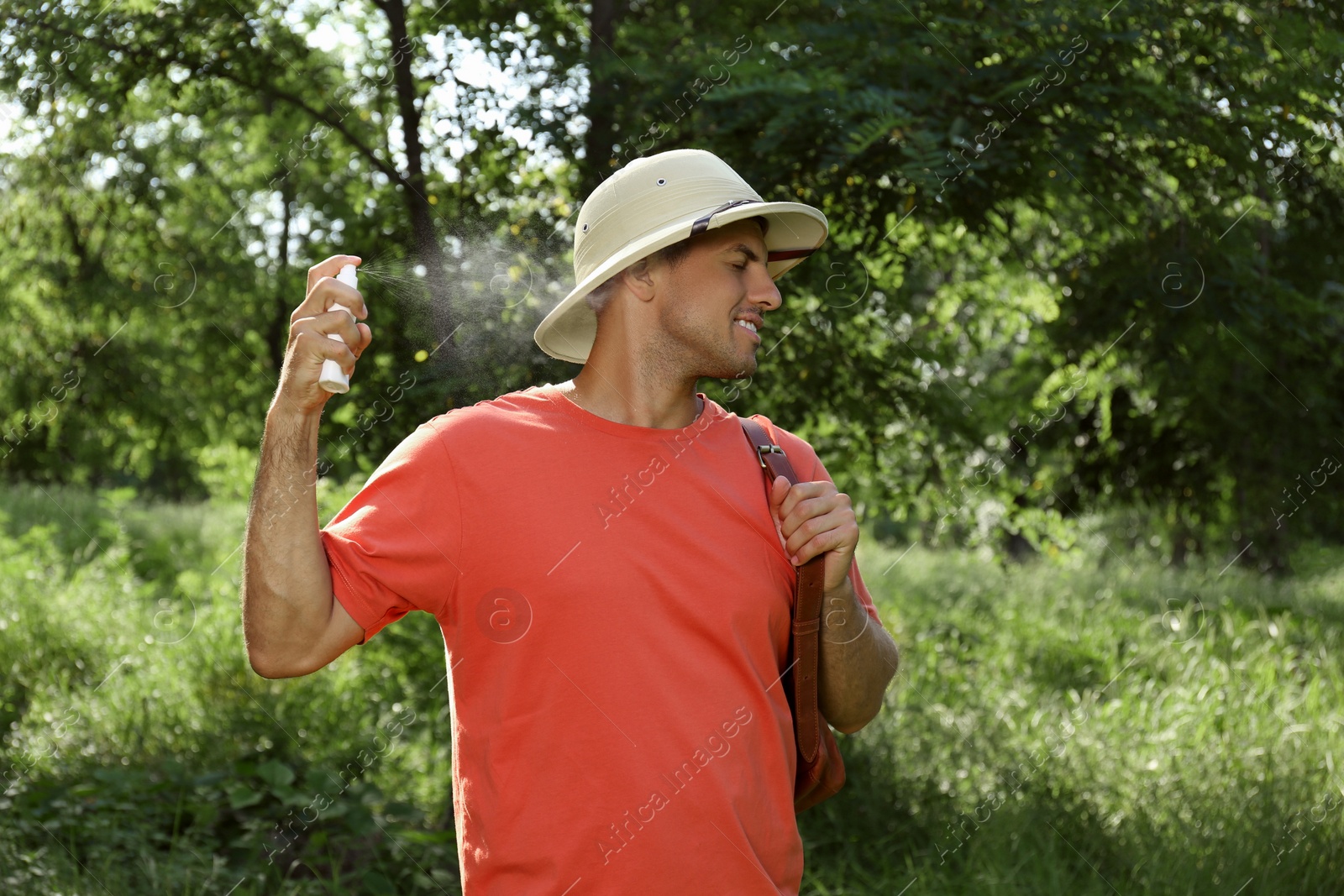 Photo of Man spraying tick repellent on neck during hike in nature