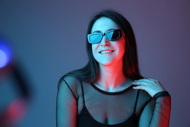 Photo of Portrait of beautiful young woman with sunglasses on color background