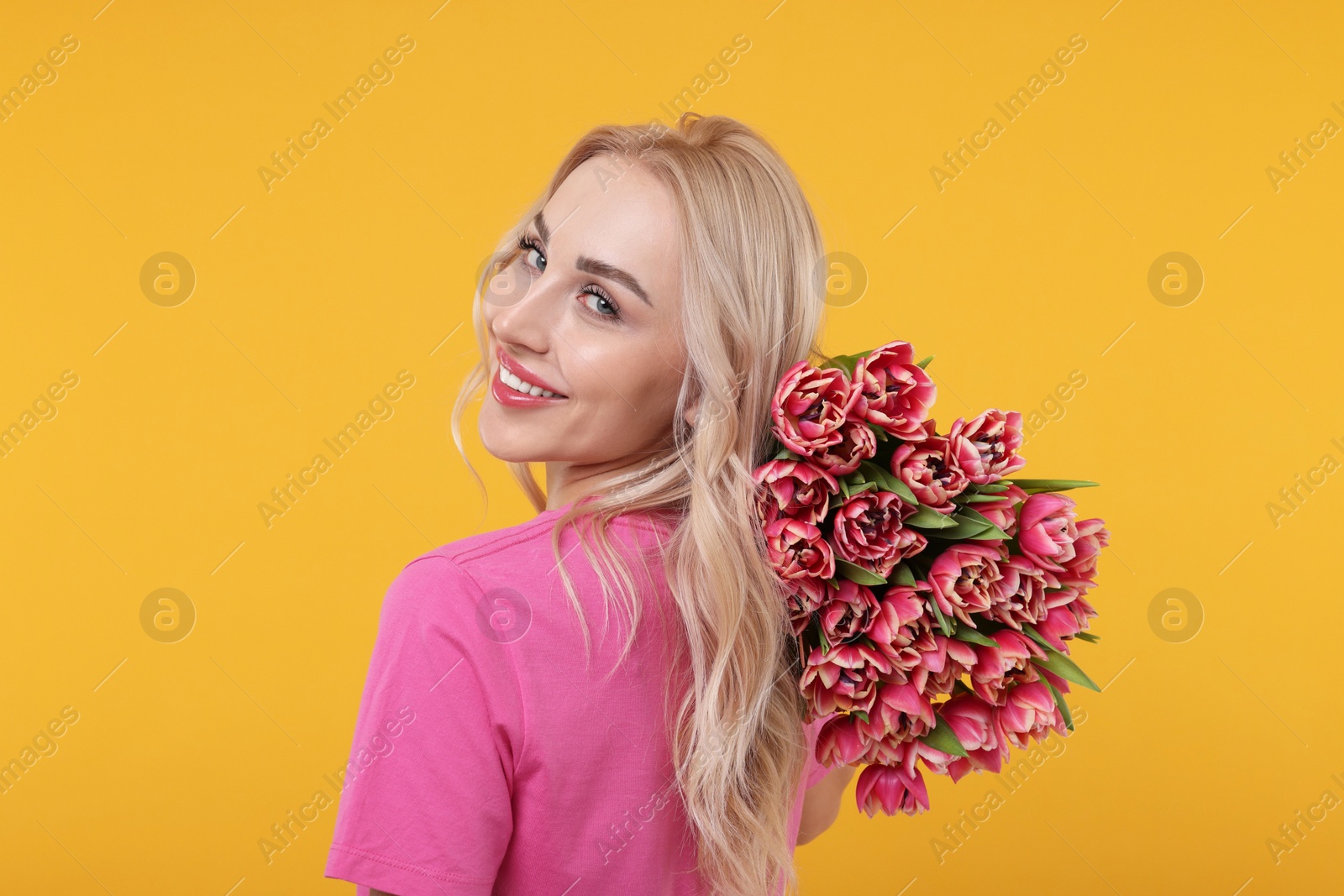 Photo of Happy young woman with beautiful bouquet on orange background