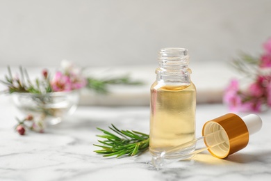 Photo of Composition with bottle of natural tea tree oil on white marble table. Space for text