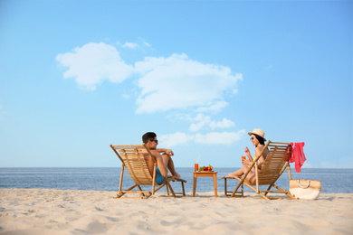 Photo of Couple resting on sunny beach at resort. Space for text