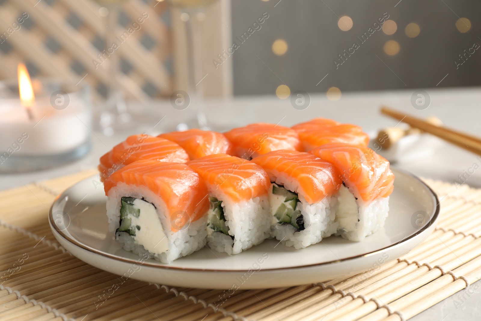 Photo of Tasty sushi rolls served on table against blurred lights, closeup