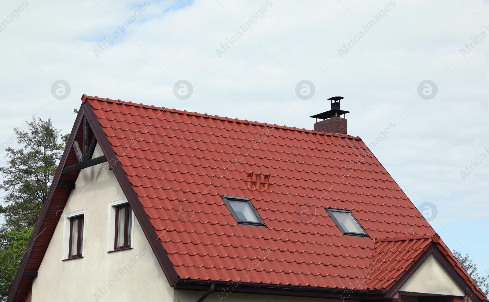 Photo of Modern house with red roof against cloudy sky