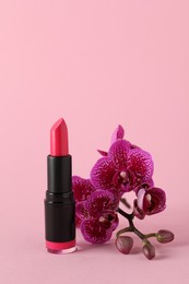 Photo of Beautiful lipstick and orchid flowers on pink background