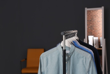 Wardrobe rack with stylish clothes in dressing room. Space for text