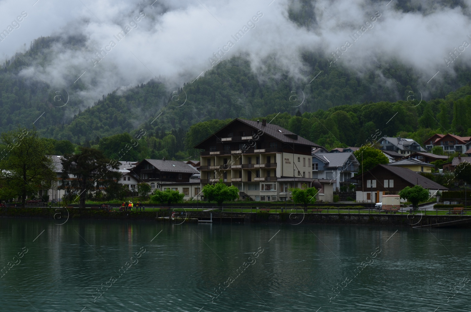 Photo of Picturesque view of beautiful village on lake shore near mountains