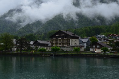 Picturesque view of beautiful village on lake shore near mountains