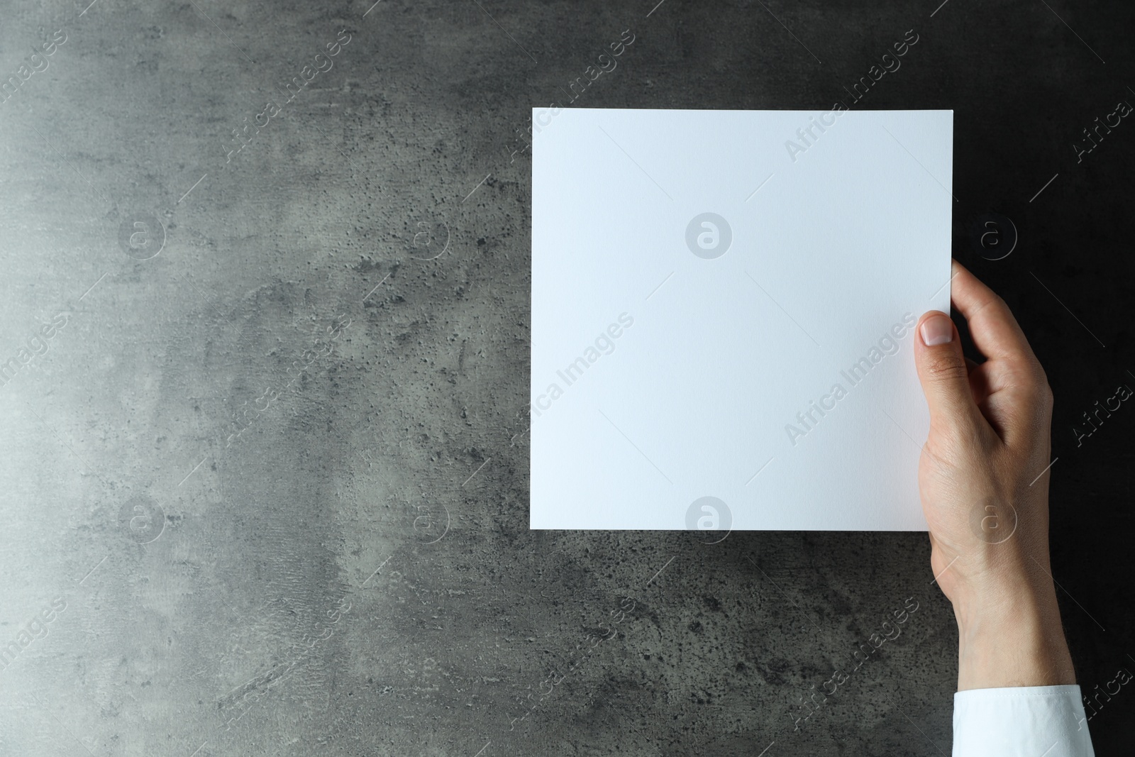 Photo of Man holding blank book at black textured table, top view. Mockup for design