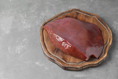 Photo of Piece of raw beef liver on grey table, space for text