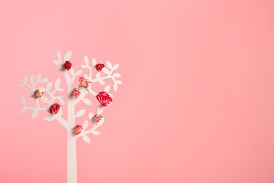 Photo of Decorative tree with flowers on color background, space for text