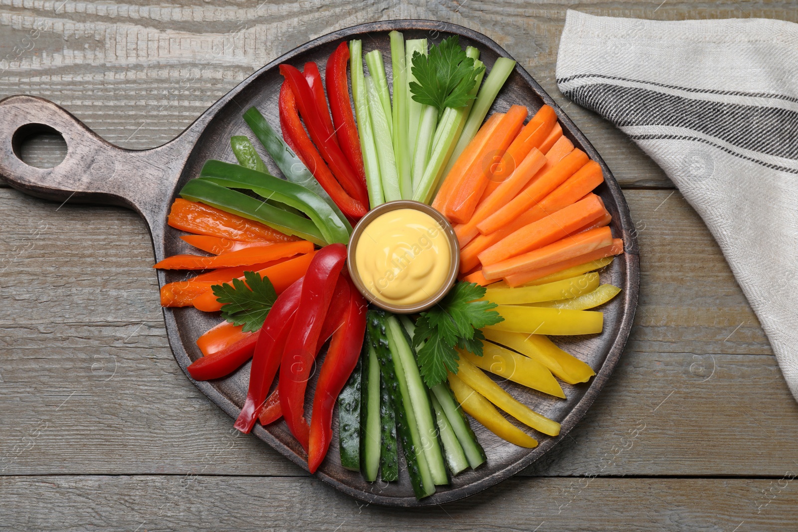 Photo of Different vegetables cut in sticks and dip sauce on wooden table, flat lay