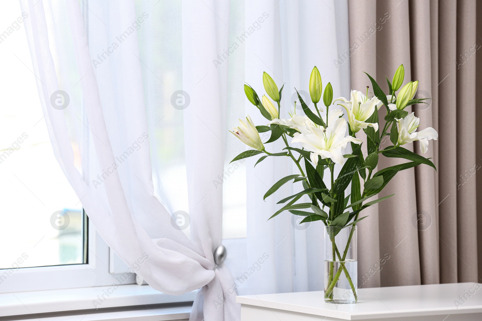 Photo of Vase with bouquet of beautiful lilies on white table indoors. Space for text