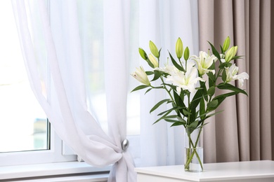 Photo of Vase with bouquet of beautiful lilies on white table indoors. Space for text