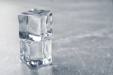 Photo of Crystal clear ice cubes on grey table. Space for text