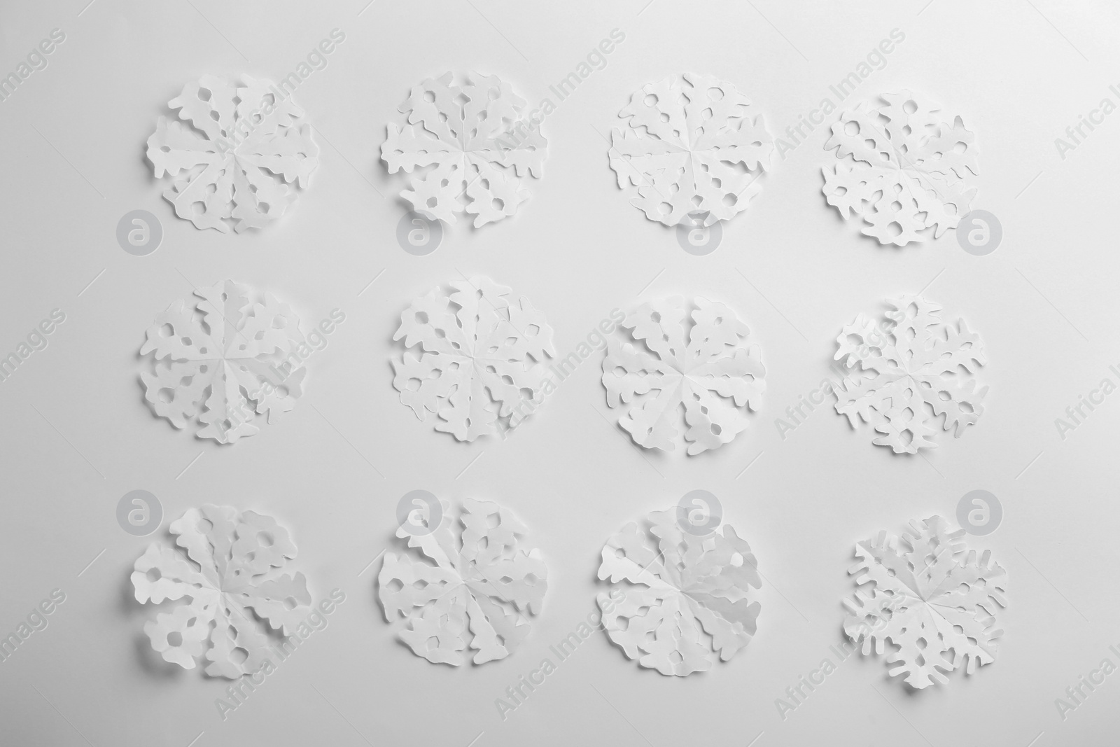 Photo of Many paper snowflakes on white background, flat lay