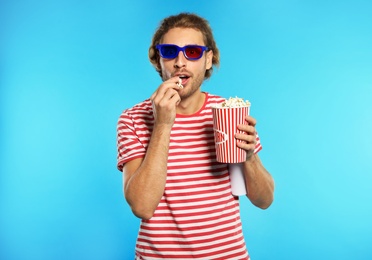 Photo of Emotional man with 3D glasses and popcorn during cinema show on color background