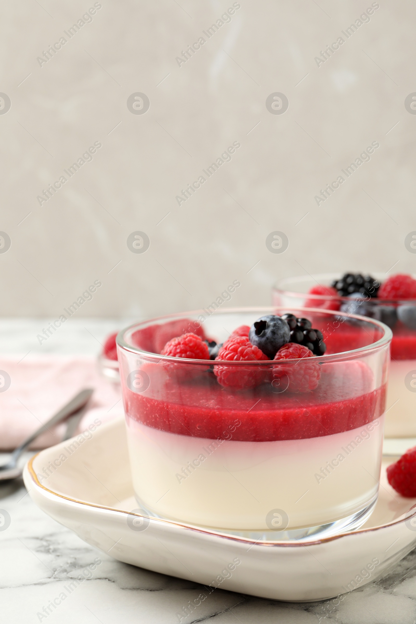 Photo of Delicious panna cotta with fruit coulis and fresh berries served on white marble table