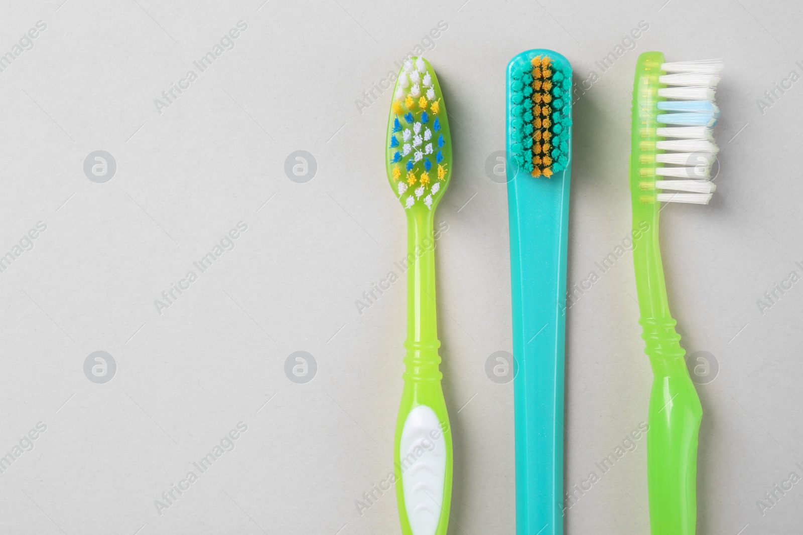 Photo of Many different toothbrushes on light background, flat lay. Space for text