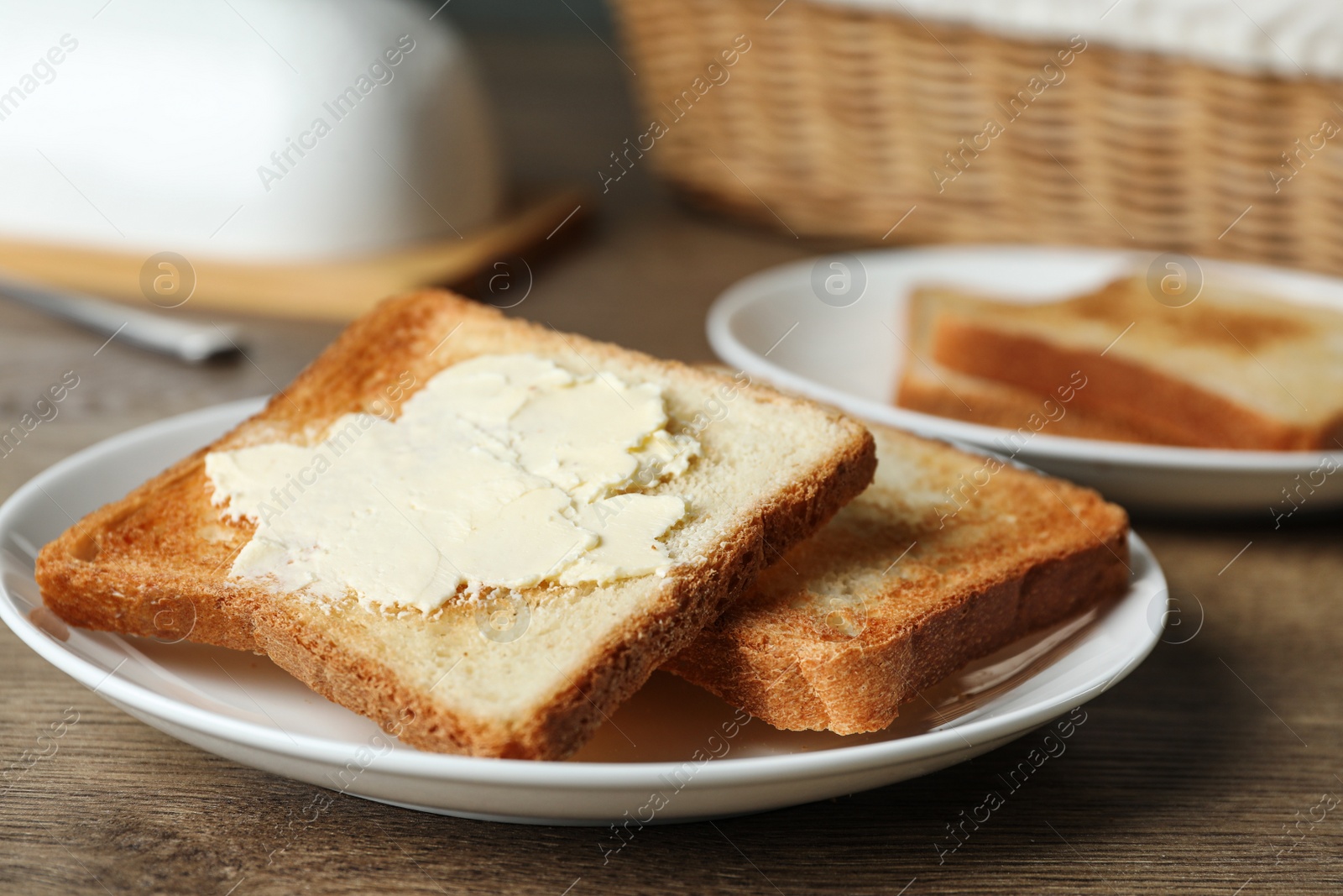 Photo of Crispy toasted bread with butter on wooden table, closeup