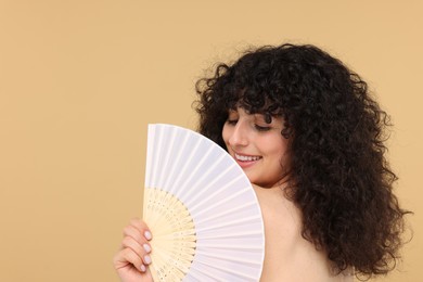 Photo of Happy woman holding hand fan on beige background. Space for text