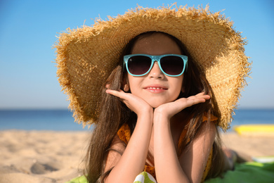 Photo of Cute little child lying at sandy beach on sunny day