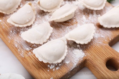 Photo of Raw dumplings (varenyky) on wooden board, closeup