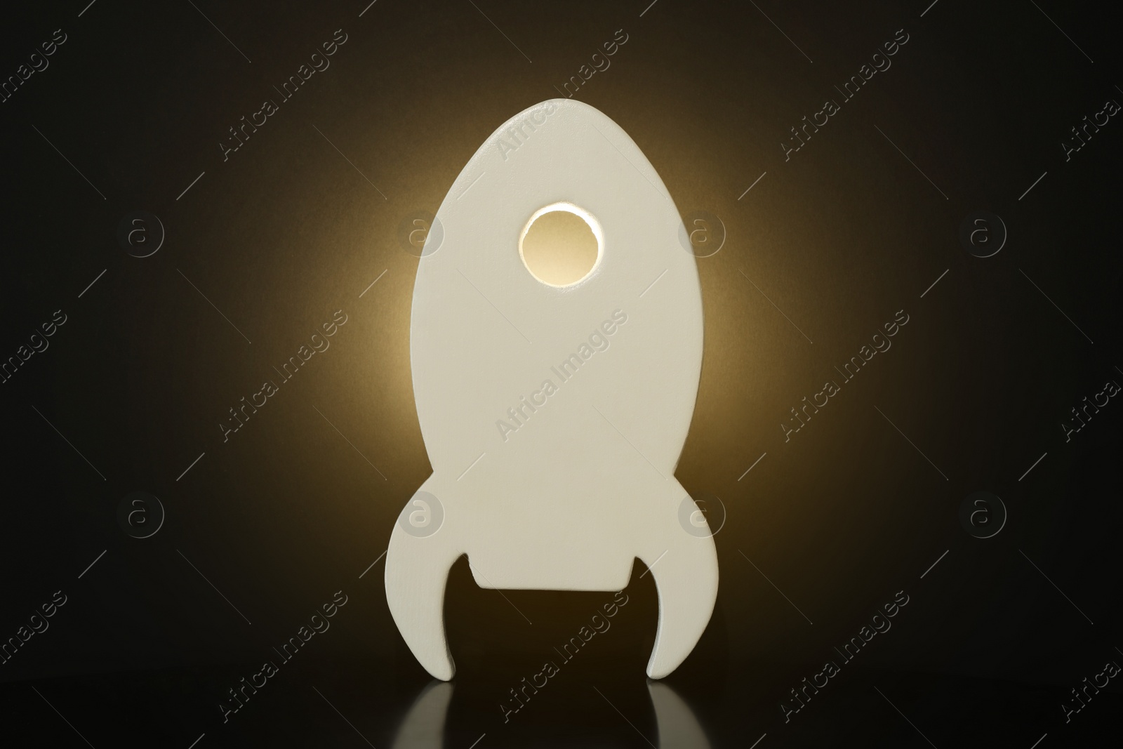 Photo of Rocket shaped glowing night lamp on black background