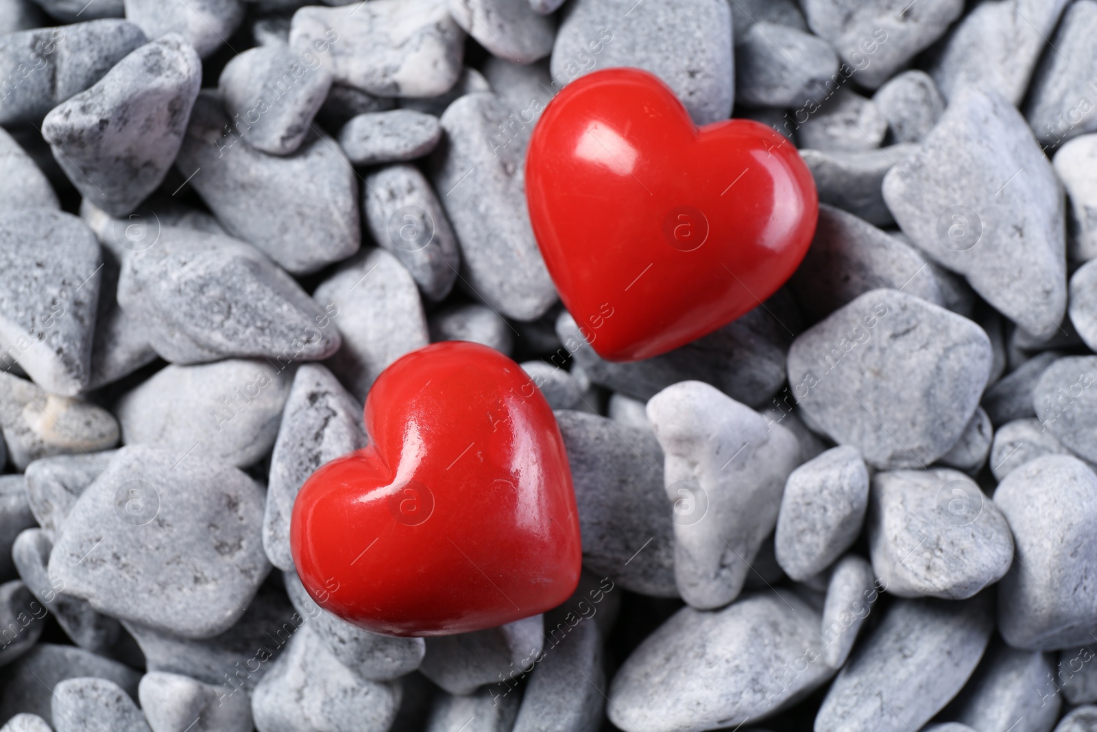 Photo of Red decorative hearts on grey stones, top view