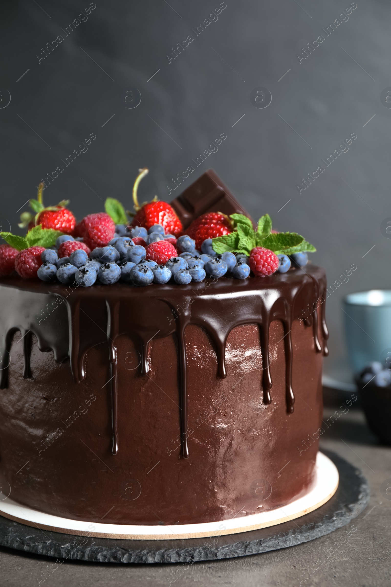 Photo of Freshly made tasty chocolate cake decorated with berries on grey table