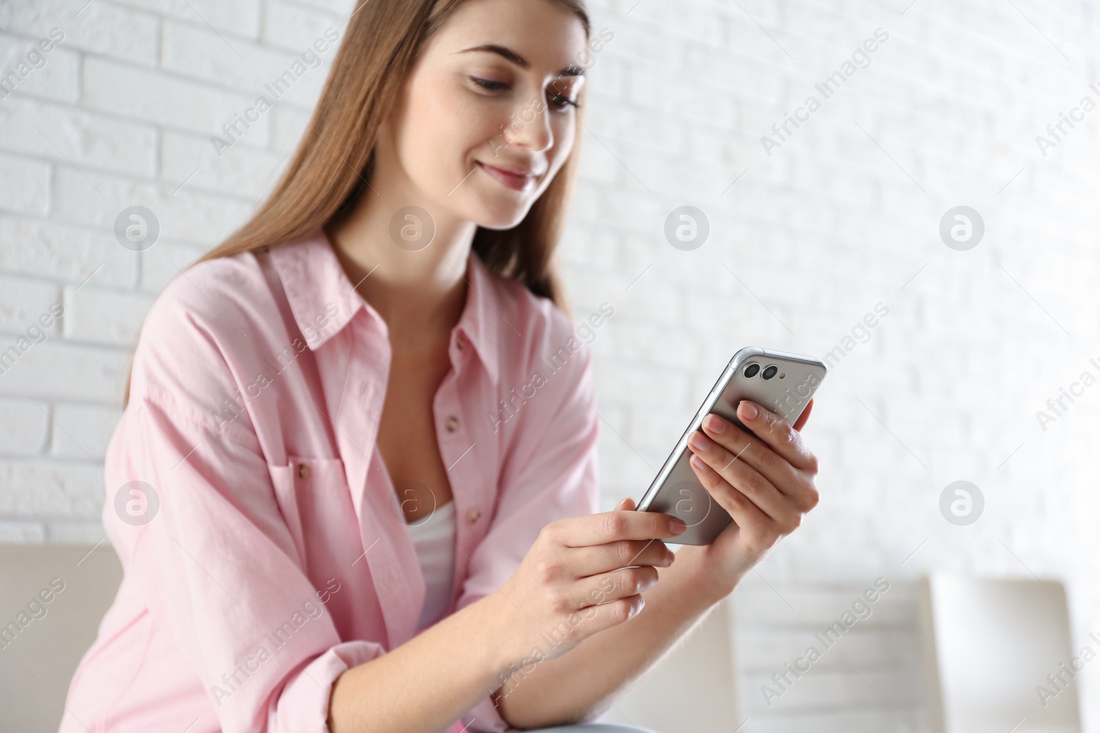 Photo of Young woman using modern smartphone indoors, closeup