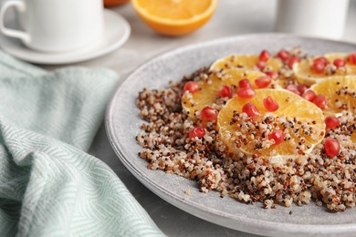 Photo of Plate of quinoa porridge with orange and pomegranate seeds on table, closeup